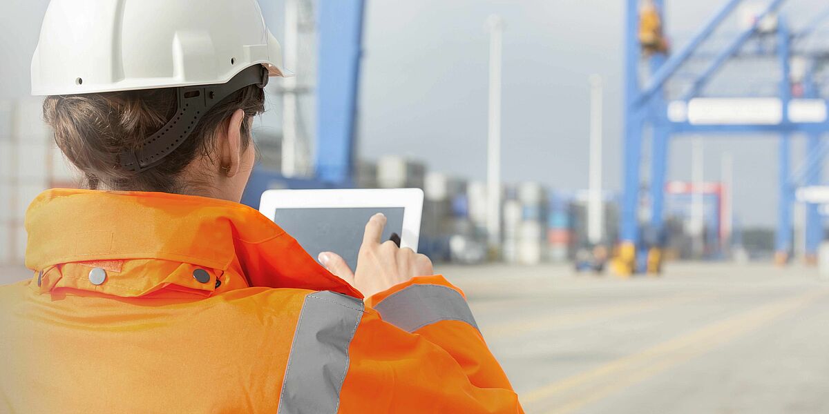 Woman using digital tablet at container port