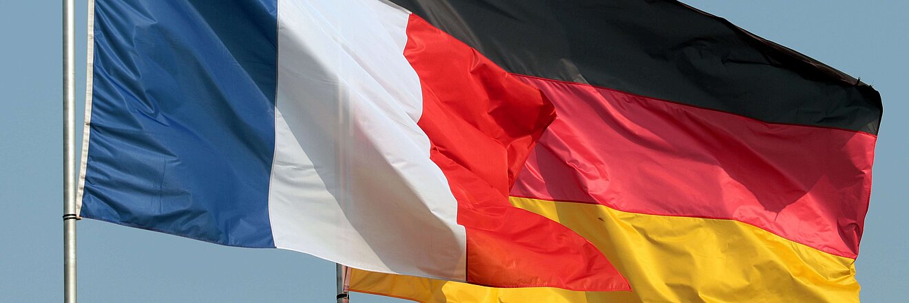 Flaggen Deutschlands und Frankreichs wehen einträchtig vor blauem Himmel...